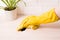 a hand in a yellow rubber glove wipes a table with a yellow microfiber rag