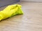 Hand in yellow rubber protective glove cleaning dirty filthy floor with micro fiber cloth from dust indoors