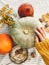 Hand in yellow sweater holding pumpkin and nuts,  flowers, fall leaves on rustic table, flat lay. Fall decor and arrangement on