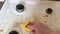 A hand with a yellow wash sponge washes the very dirty greasy surface of the gas stove. After the sponge, a clean trace remains