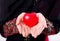 Hand of young asian muslim woman holding red heart shaped pillow closeup