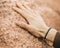 A hand of a young boy touching the sand