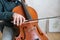 Hand of young cello player gliding fiddlestick across strings