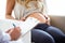 Hand of young doctor giving a routine check to beautiful pregnant woman and writing results.