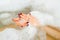 The hand of a young girl in the water with foam in bathtub