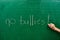 Hand of a young girl writing the words NO BULLIES on the green school board