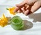 Hand of young woman and glass jar with natural green kiwi fruits scrub