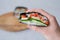 The hand of young woman, holding  onigirazu, vegan sushi sandwich with vegetables cucumber, pepper, spinach and tofu. Trend Japa