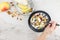 The hand of a young woman with a spoonful of granola filled during breakfast. plate with granola, berries, ripe pear. blended food