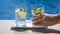 Hand of a young woman takes a glass of fresh lemon infused mineral water