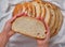 Hand of young woman takes a piece of homemade rustic bread