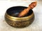 Handcrafted brass singing bowl with wooden stick put on the floor. Isolate background