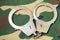 Handcuffs on camouflage fabric background