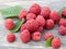 Handful of fresh raspberries with green leaves laid out on a wooden background