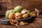 A handful of green young walnuts on a wooden background together with an old nutcracker. Nuts with shell and walnuts in green peel