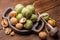 A handful of green young walnuts on a wooden background together with an old nutcracker. Nuts with shell and walnuts in green peel