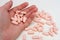 A handful of pink pills. Man holds vitamins in the palm of his hand