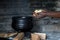 A handful of potatoes being put into a black cast iron pot on a wood fire