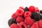 Handful of raspberry and blackberry berries on white background