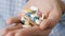 Handful of tablets and capsules of various shapes and colors lie in palm of your hand. Close-up, front view, center