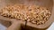 A handful of Ukrainian wheat grains falling into an old damaged cracked wooden bowl