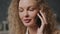 Handheld close up of a young adult curly caucasian woman on a phone call indoors