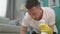 Handheld shot of man with cloth cleaning floor uses rag and fluid in a spray