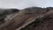 Handheld steep rocky slope of volcanic mountain summit in fog and mist