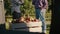 Handheld view of a full crate of apples and two farmers in the background