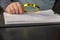 Handholds a gold-rimmed magnifying glass atop a clipboard. Adult male examining documents with handwritten text. Close-up.