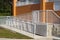 Handicap ramp with white railing and orange wall