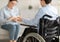 Handicapped adolescent in wheelchair having consultation with psychologist at office, free space