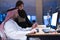 Handicapped Arabic businessman in tradition suit with female arabic assistent working in office. Disabled businessman in the