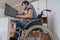 Handicapped disabled man on wheelchair is working with computer in office