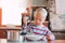 A handicapped down syndrome child pouring soup into a plate indoors.