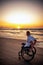 Handicapped man in wheelchair and his girlfriend alone on a beach at sunset