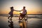 Handicapped man in wheelchair and his girlfriend on a beach at sunset