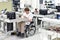 handicapped worker in a wheelchair assembling electronic components in a modern factory at the workplace