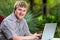 Handicapped young man typing on laptop in garden.