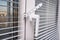 A handle and a restrictor, window stopper or limiter on PVC double glazed window with horisontal aluminium blinds close up