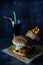 Handmade burger with fries and coke with straws on dark background