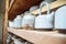 Handmade ceramic teapots on a shelf in the master`s workshop. Beautiful author`s ceramic ware of blue color. An original
