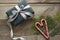 Handmade chistmas present from black wrapping paper, silver ribbon and candy cane in shape of heart on wooden surface. Top view an