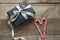 Handmade chistmas present from black wrapping paper, silver ribbon and candy cane in shape of heart on wooden surface. Top view an