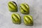 Handmade chocolate candies with green shining coating with black drops on a white matte glass background