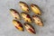 Handmade chocolate candies with yellow shining coating with red drops in the form of a lancet on a white matte glass background