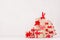 Handmade christmas gifts of kraft and christmas tree of with festive red ribbons and bows on white wood background.