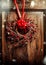 Handmade Christmas wreath hanging on aged old wooden door with red ribbon and berries with snow