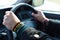 Handmade DIY friendship bracelet with Rasta flag pattern with a peace symbol on wrist. Hands holding steering wheel in the car.