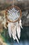 Handmade dream catcher with white doily on background of rocks a